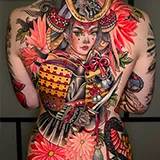 Neo-Traditional full-back tattoo of a female samurai wearing a ceremonial outfit and ornate headpiece, surrounded by large pink flowers, designed by Lacey Griffiths at House of Wolves Tattoo, Geelong