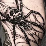 Realistic fine-line spider tattoo with a web between its legs and a skull on its back, designed by Scott Russell at House of Wolves Tattoo, Geelong